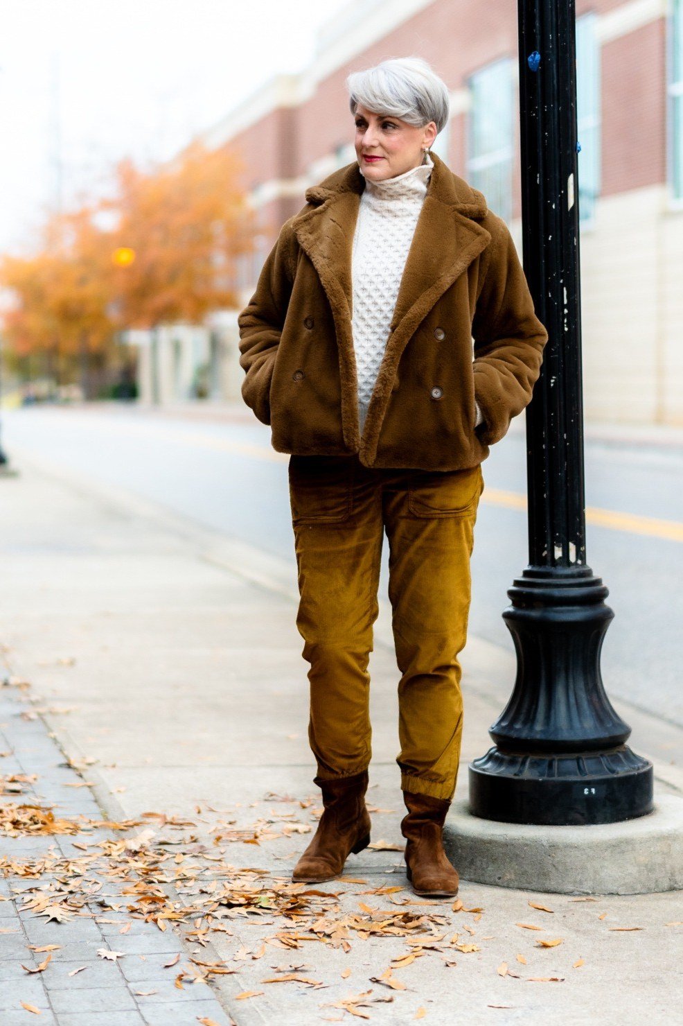 Brown shearling jacket with mustard corduroy trousers and cream turtleneck