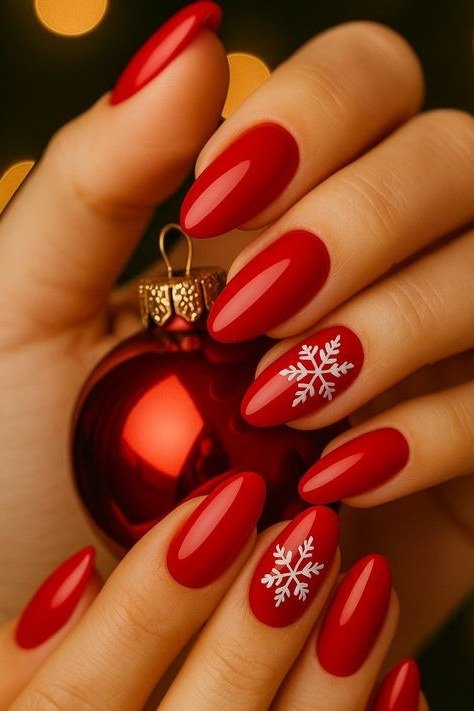 red nails with snowflakes holding christmas ornament by tree