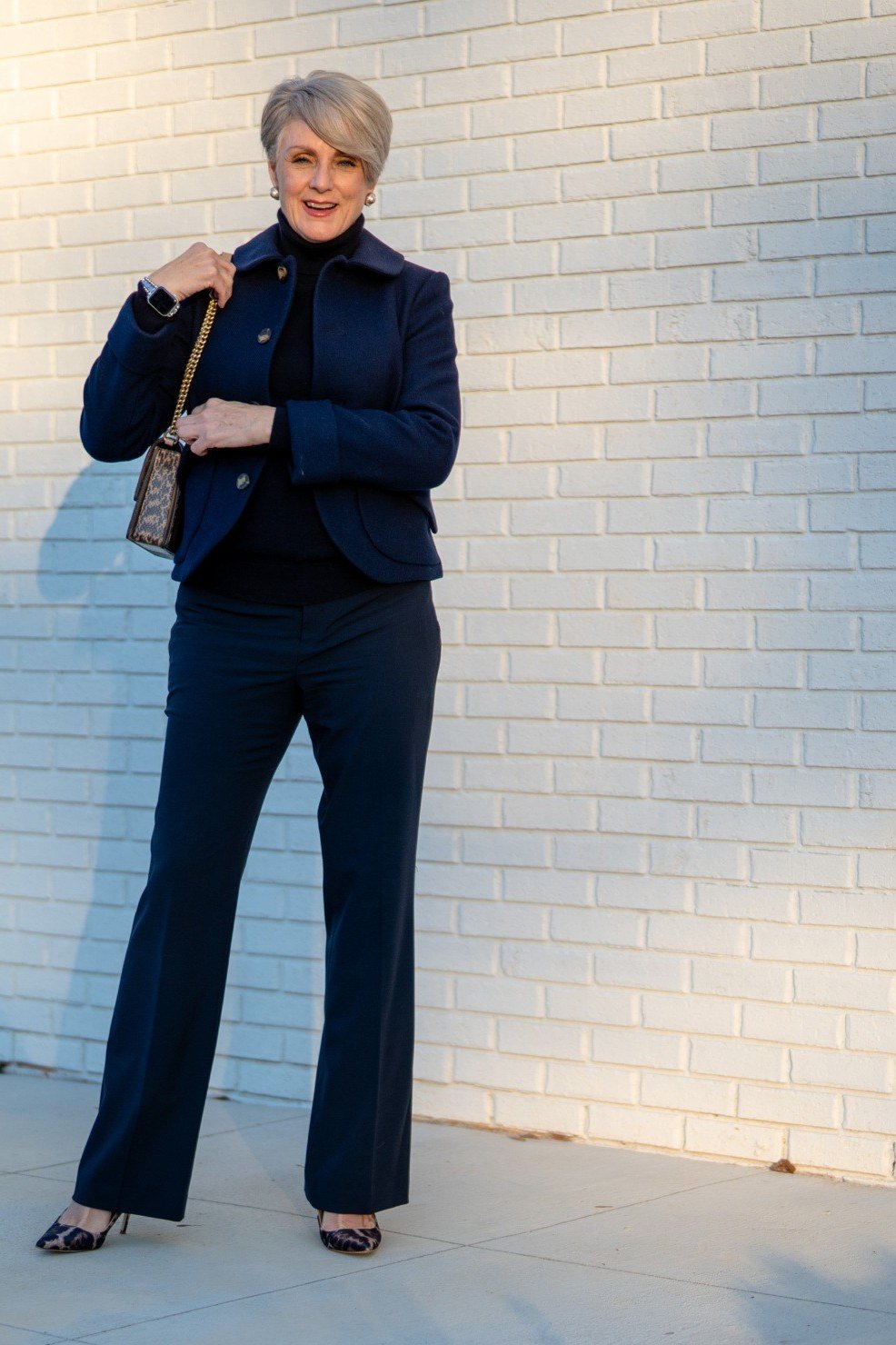 Older woman in navy blazer black turtleneck and navy trousers
