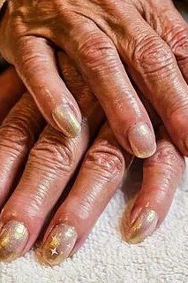 Starry Gold Glitter Nails - gold glitter elderly hands star accents, glitter winter nail design for women over 60