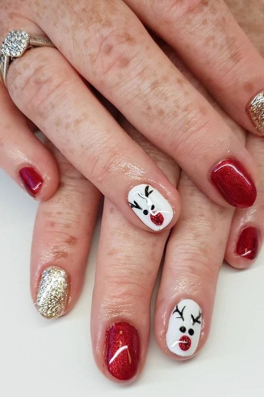 Mature hands, classic red nails with white reindeer face and gold glitter accent - classy Christmas nail idea for women over 70
