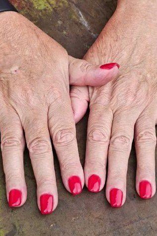 Fiery siren red nail polish on older hands