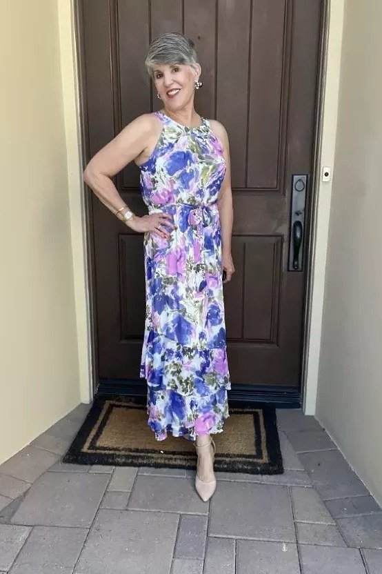 Older woman in a blue-and-purple floral halter maxi dress, standing in a doorway - summer dress for women over 50