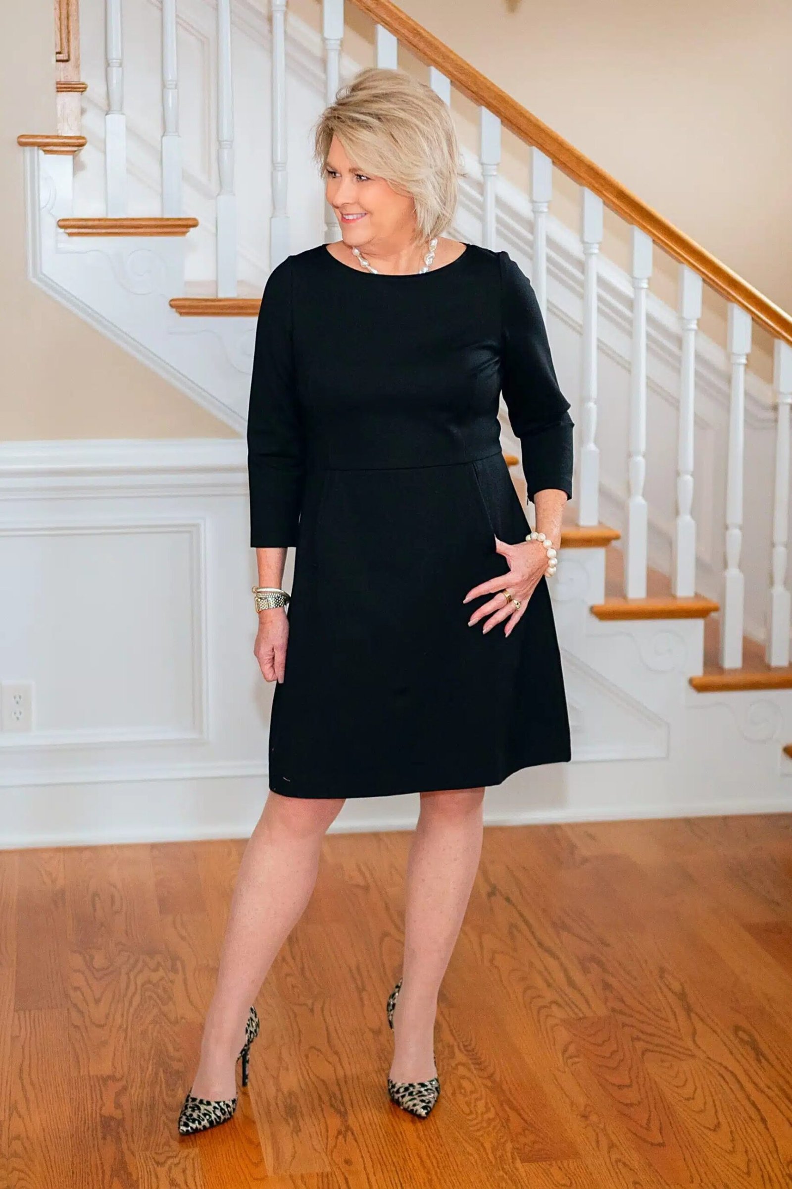 Black three-quarter-sleeve sheath dress on stairs for women over 50