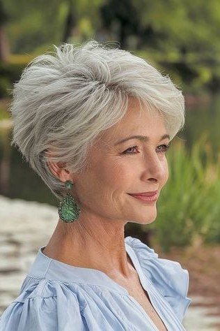 Silver pixie haircut with feathered sides and green drop earrings for older women
