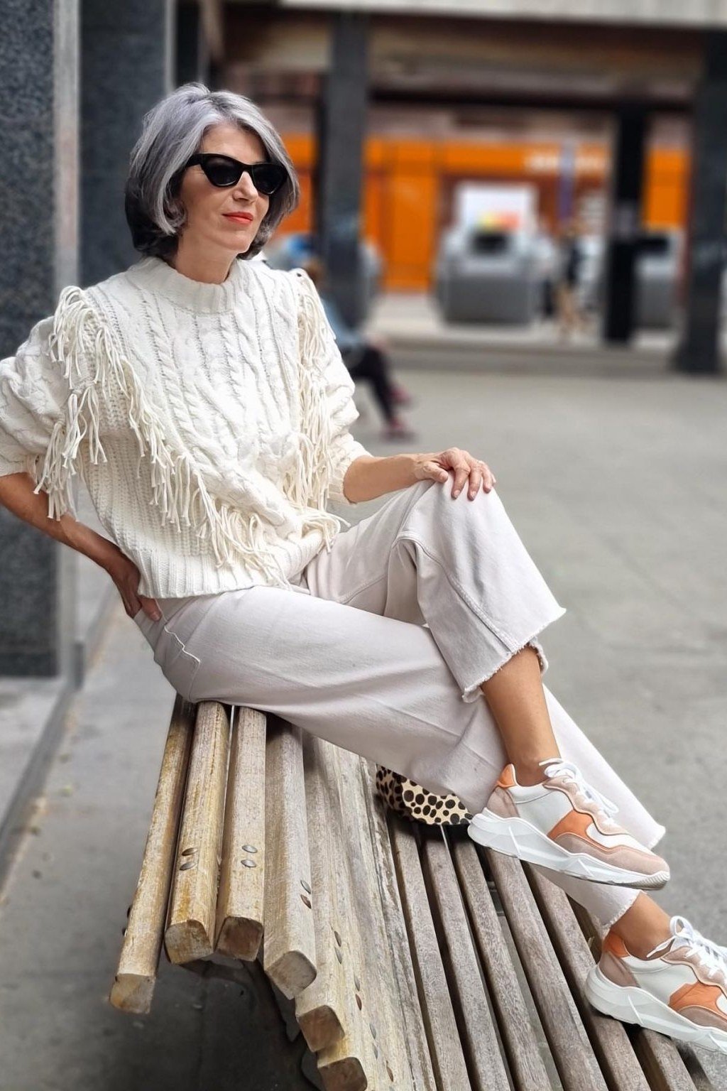 Casual fall outfit for women over 60: cream chunky knit cardigan, white trousers, tan mules