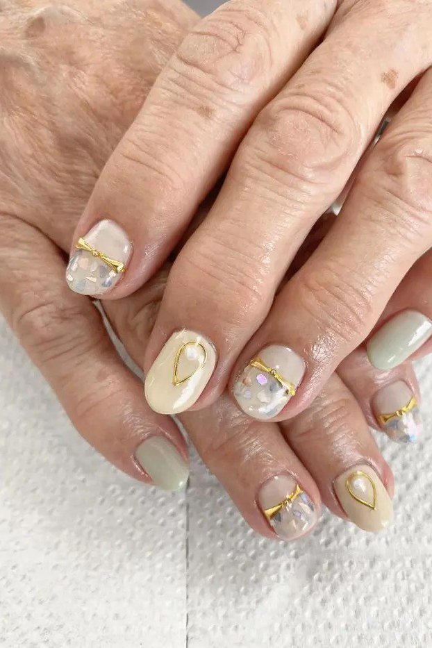 Nail art design for women over 60: beige nails with gold foil accents on older hands