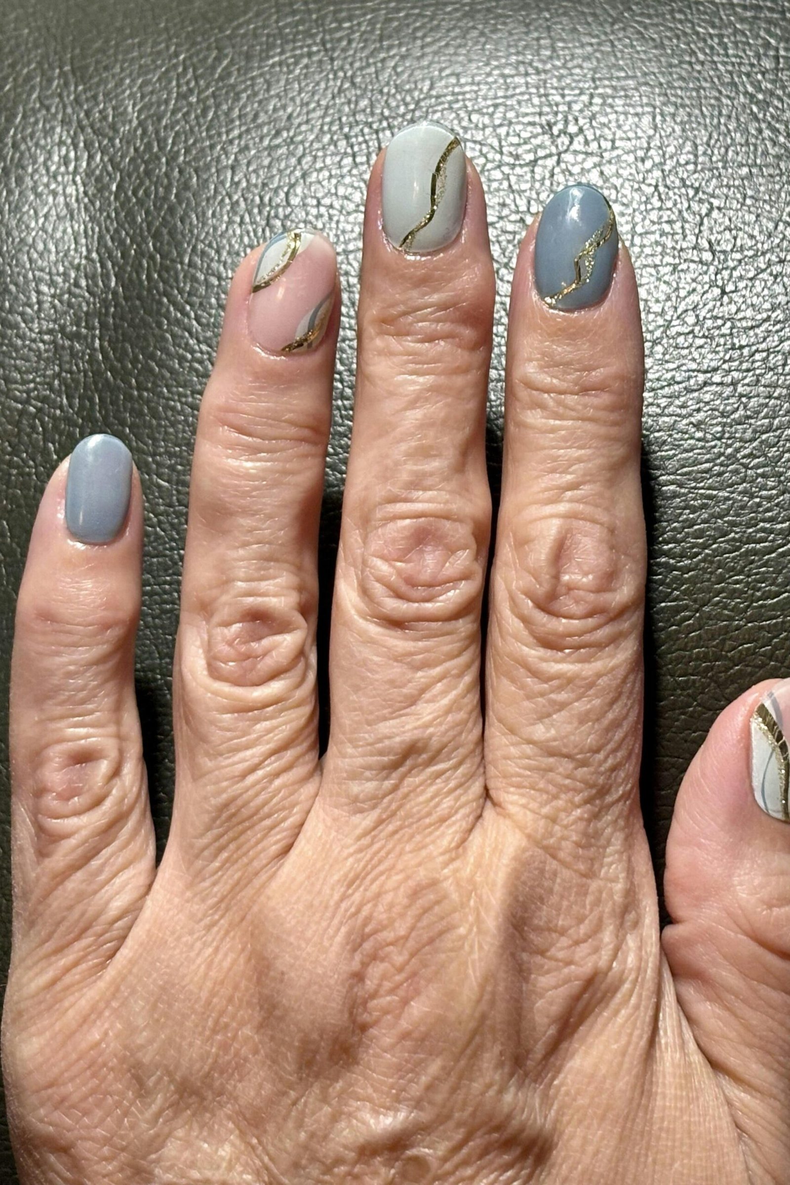 Grey nails with white line art on older woman's hand
