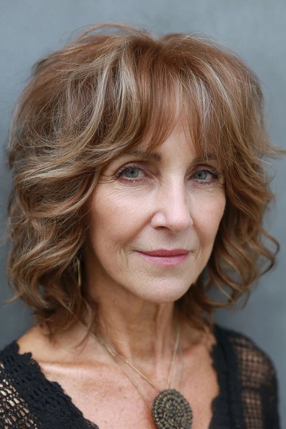 Wavy copper-brown hair with bangs on an older woman, front view, medium hairstyle for women over 60