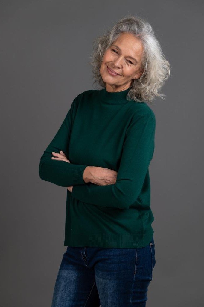 older woman in emerald green turtleneck with blue jeans