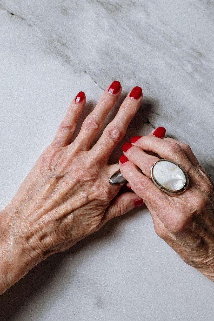 glossy red nails styled on cool marble for older women