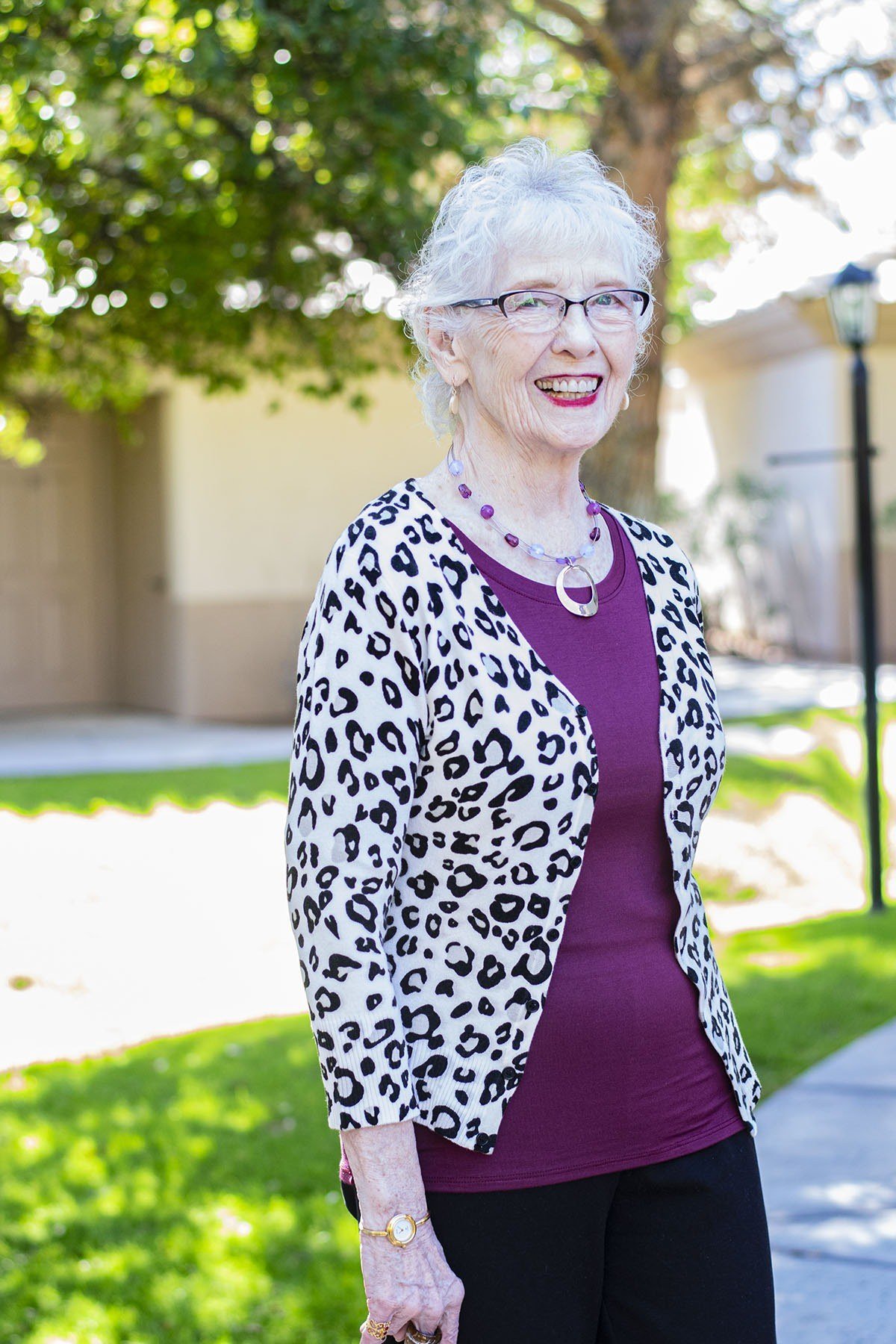 Older woman wearing a leopard print jacket over a magenta top with black trousers