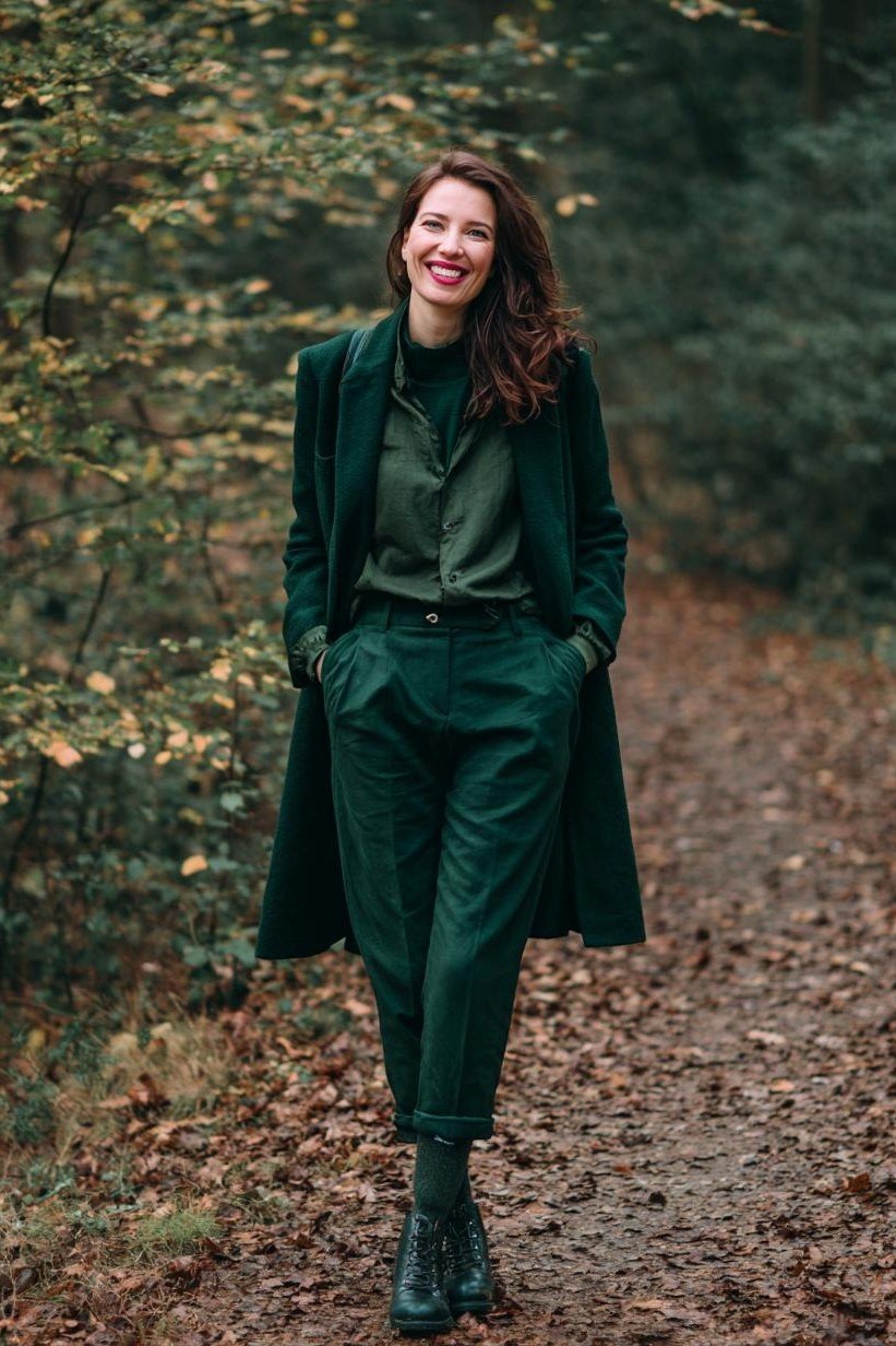Older woman in emerald green pantsuit with coat and boots