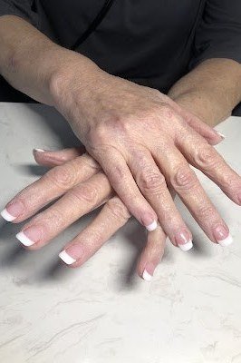 Classic French manicure with hands crossed on marble