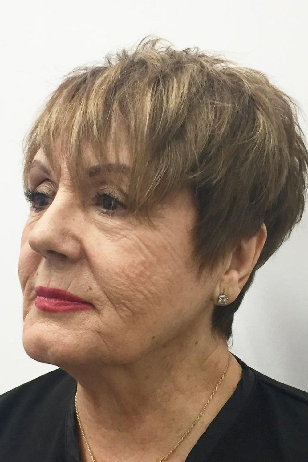 Silver pixie haircut for women over 70 in pink blazer, front view