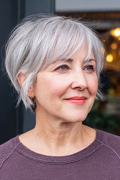Silver pixie with side-swept bangs - trendy short haircut for older women with fine hair
