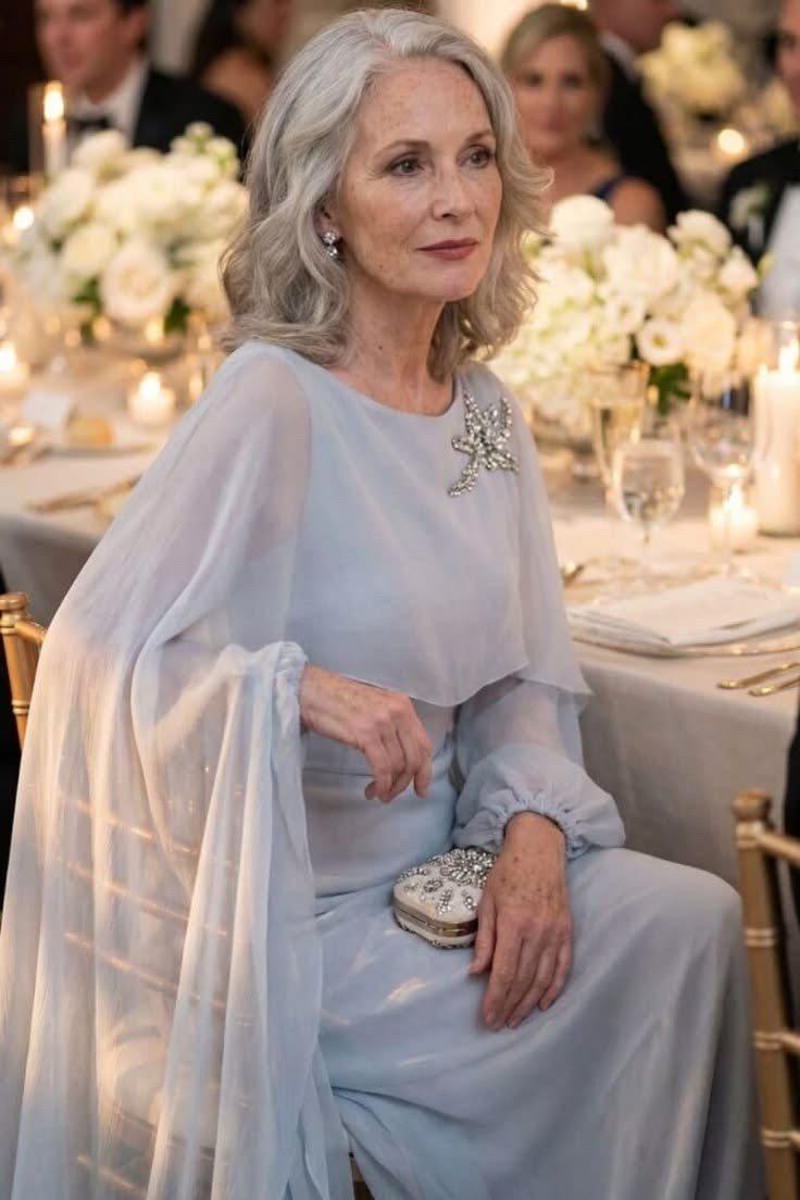 Silver-haired woman in pale blue chiffon evening gown holding a clutch