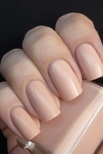 Nude nails with polish bottle on dark background