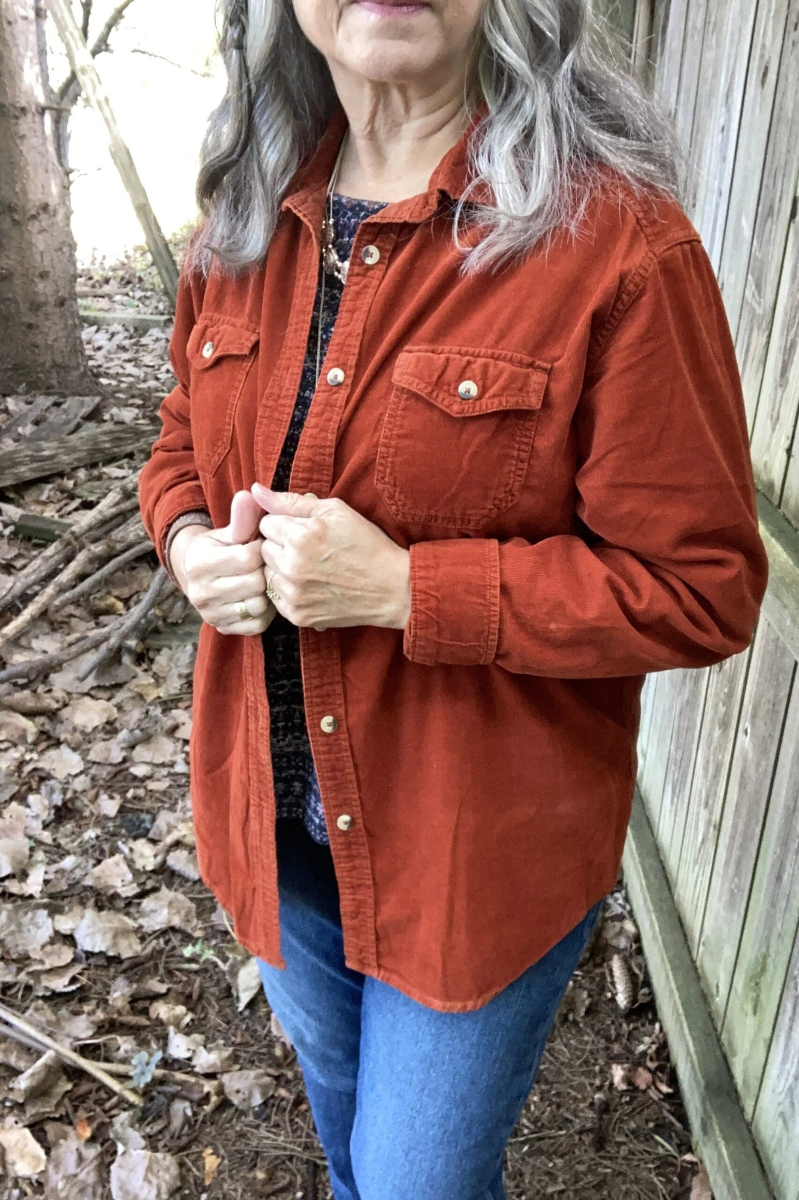 Rust corduroy overshirt with blue jeans in woodland setting