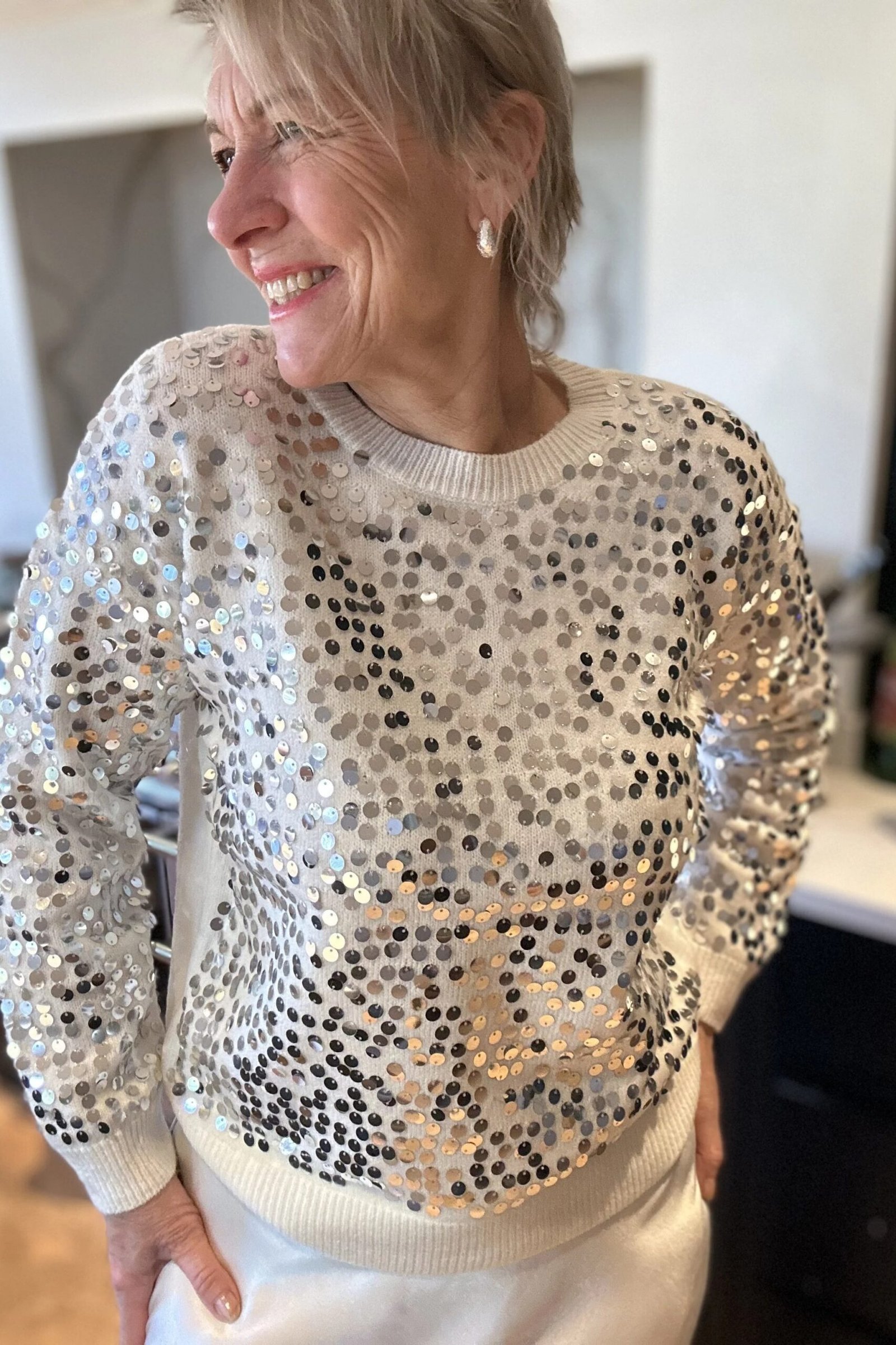 holiday evening outfit for women over 60: silver sequin sweater with white pants