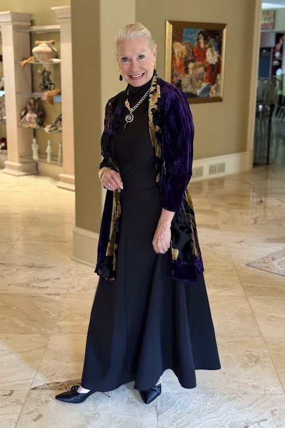 Black maxi dress with purple velvet jacket, hallway - wedding guest outfit for women over 50