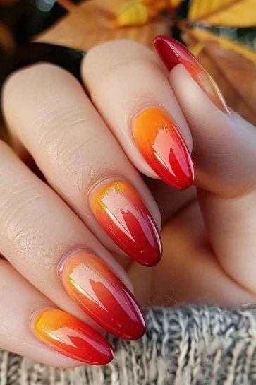 Red Orange Flame Almond Ombre - Cherry red flames into glowing orange on these medium almond nails, paired with a cozy gray sweater.