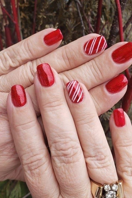 Older hands, red nails with red-and-white candy stripe accent - classy Christmas nail idea for women over 70