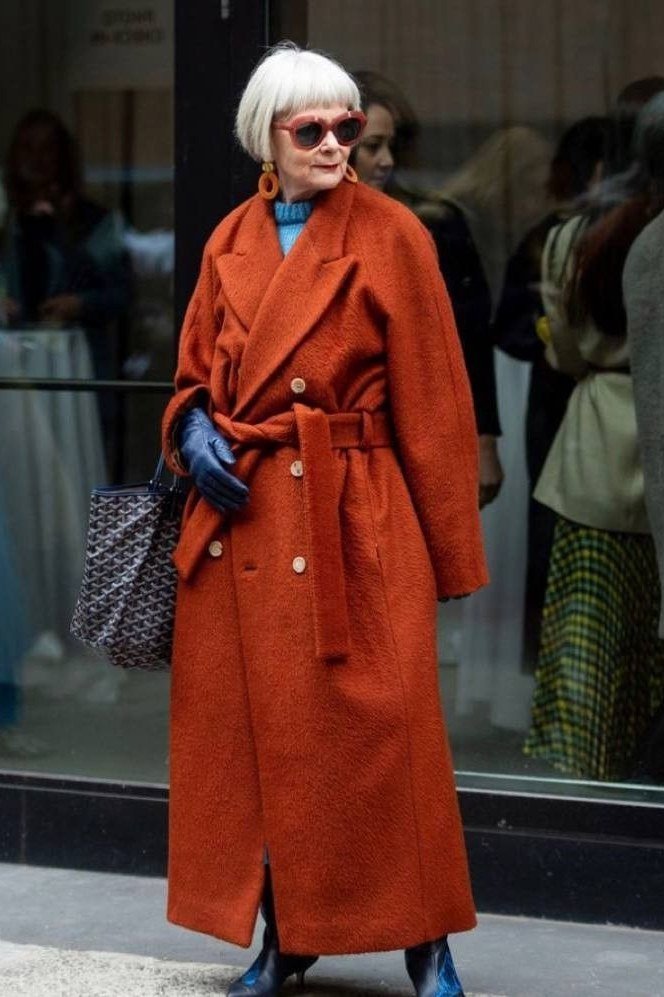 Effortlessly chic fall outfit for women over 60: burnt-orange wrap coat with blue gloves