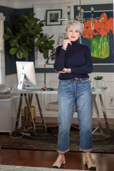 Woman over 60 wearing navy turtleneck, medium jeans, home office