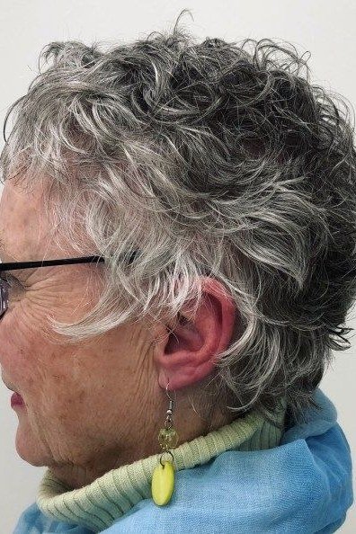 Salt-and-pepper curly bob side view with glasses - curly hairstyle for women over 60