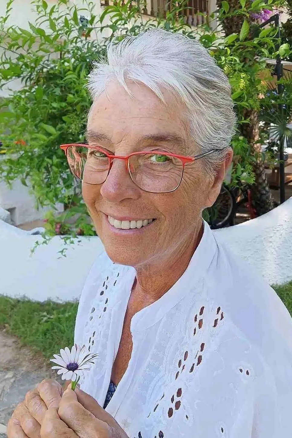 White wispy pixie haircut with feathered bangs and red glasses for women over 60