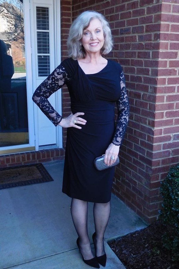 Black lace long-sleeve dress, black tights, brick exterior, chic night out outfit for women over 50