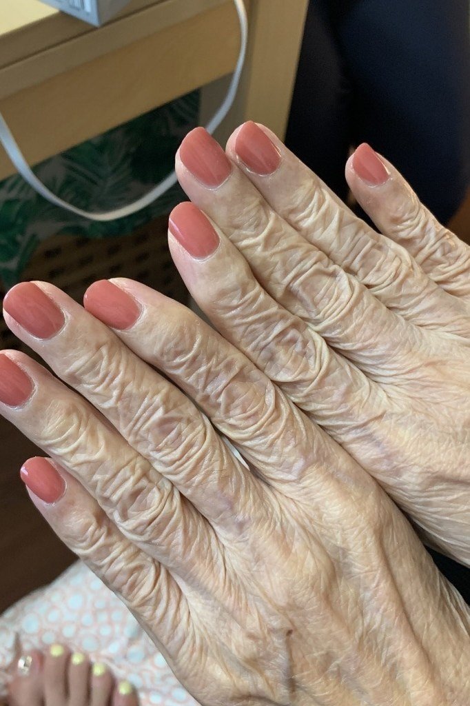 Terracotta pink nails on very wrinkled hands, best manicure idea for women over 60