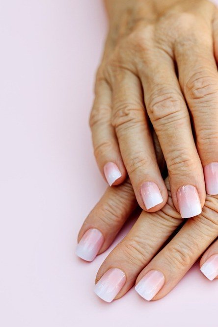 Soft pink french nails on elderly hands