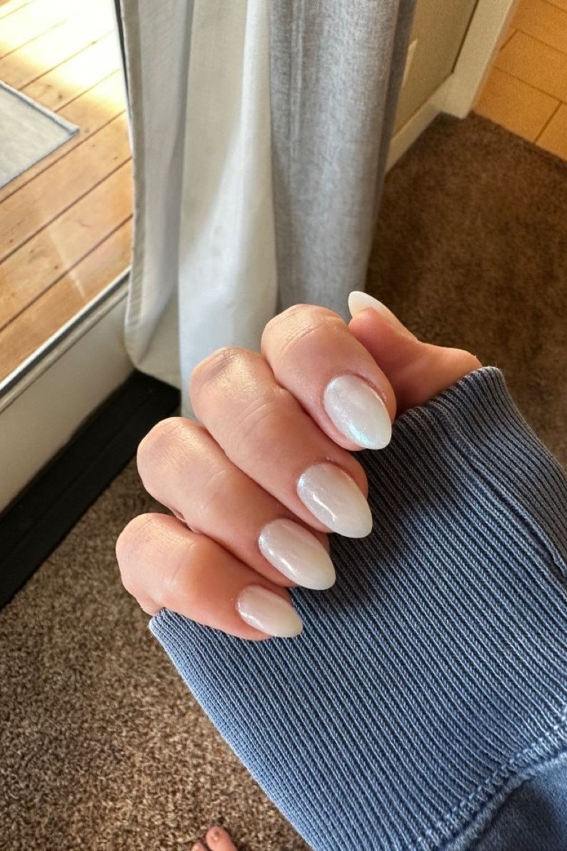 Short milky white nails photographed in natural window light