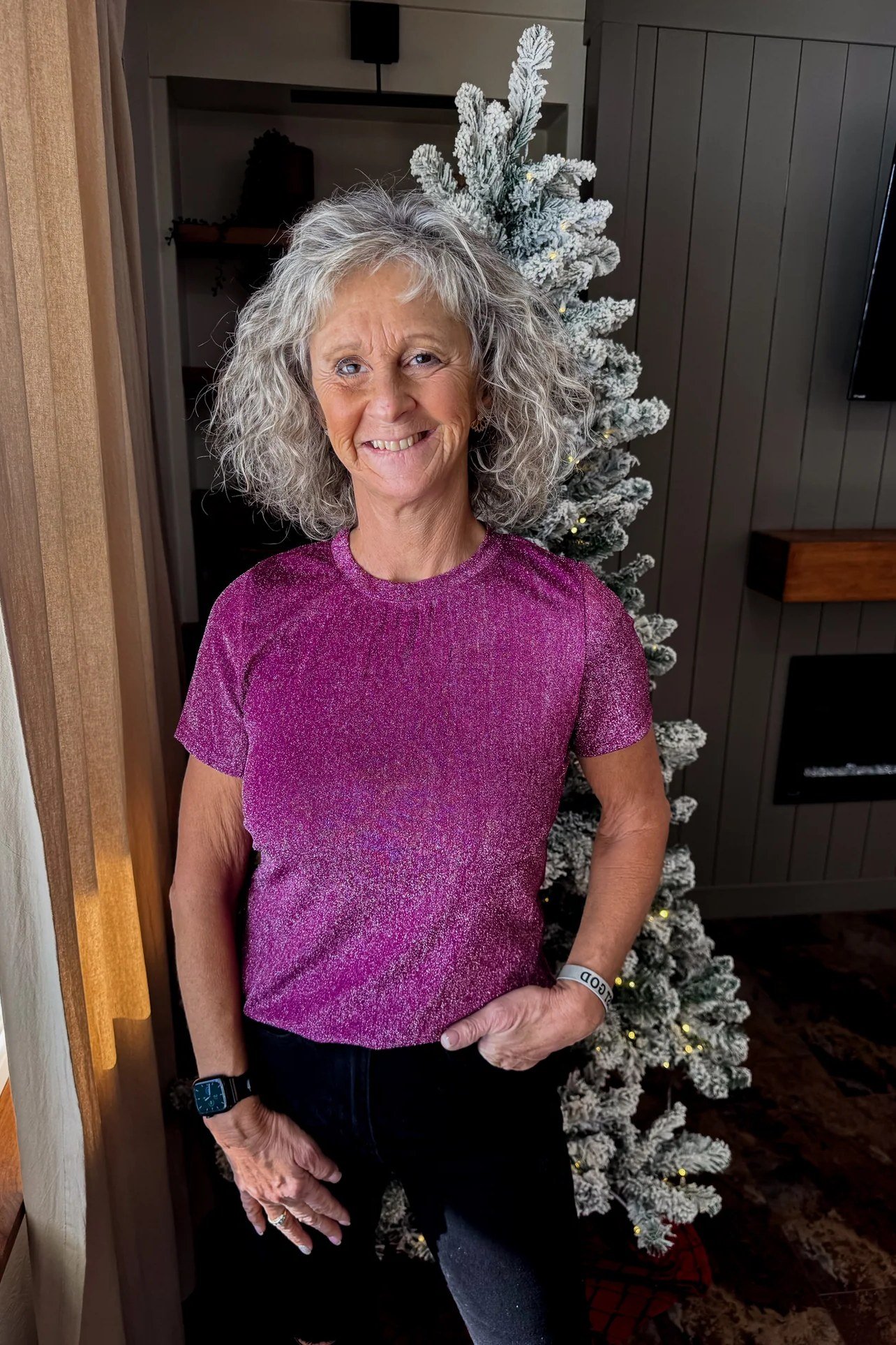 holiday evening outfit for women over 60: magenta glitter top by the christmas tree