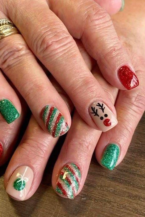 Red, green and white festive nails with reindeer and stripe art - classy Christmas nail idea for women over 70