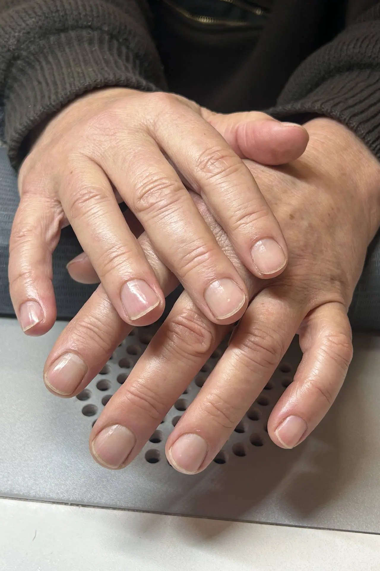 Mature hands resting on a nail dryer giving polish time to dry