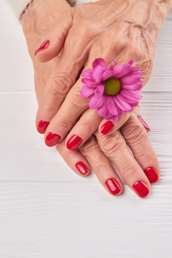 Classic red short nails on elderly hands