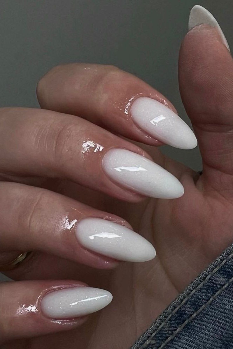 Luminous milky white almond nails on a dark background