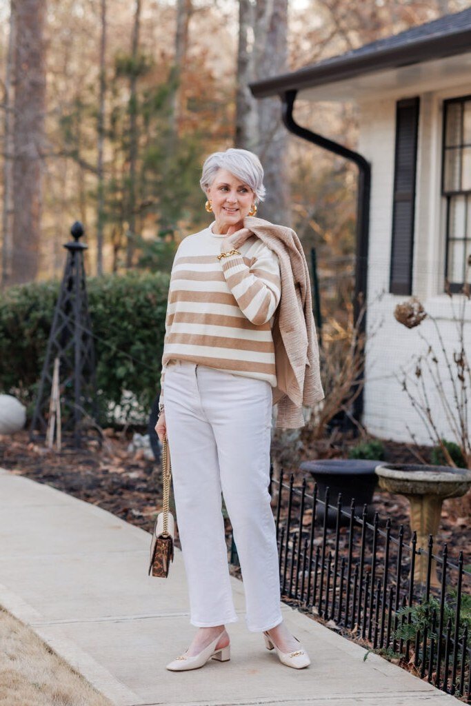 Woman over 50 wearing striped top with white jeans and sneakers, everyday casual outfit idea