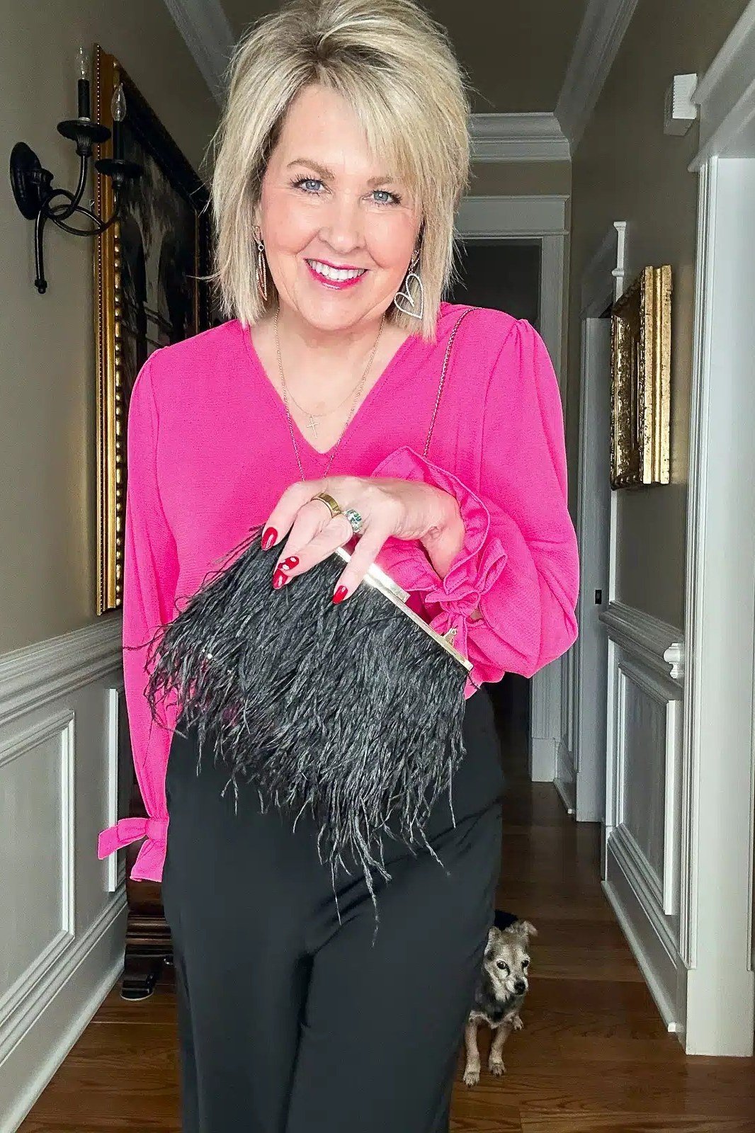 Blonde woman in fuchsia blouse with black skirt and feather clutch