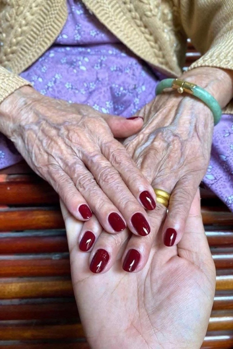 Deep burgundy nail polish on mature hands