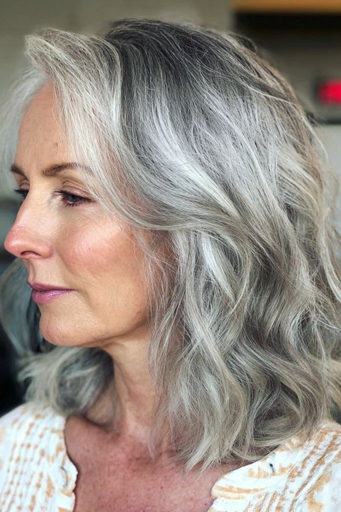 Wavy silver-gray shoulder-length haircut on an older woman, side view, medium hairstyle for women over 60