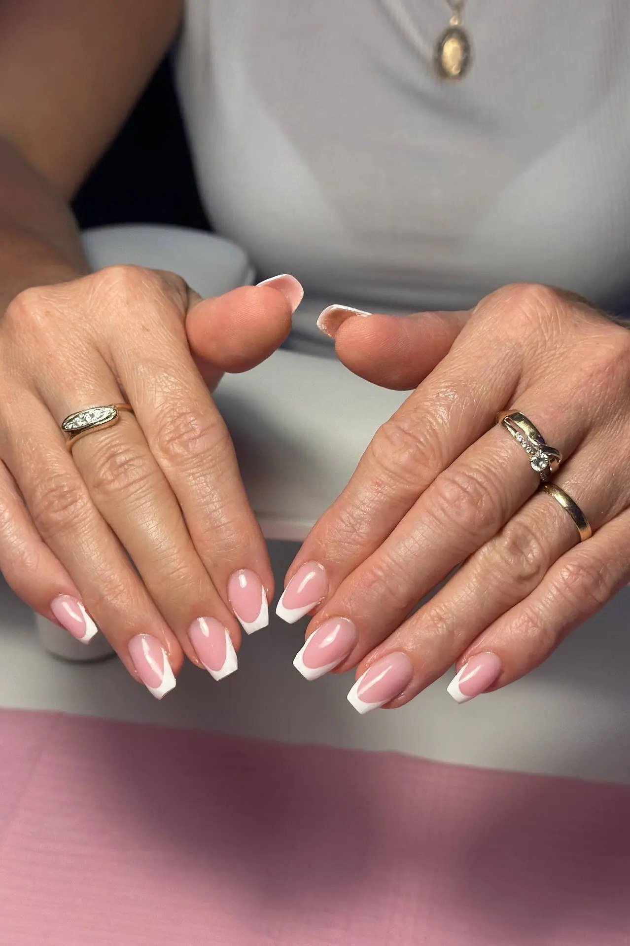 French manicure on hands resting on a pink mat