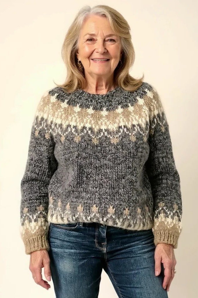 Grey fair-isle yoke sweater with jeans on beige backdrop, cozy sweater outfit idea for women over 70