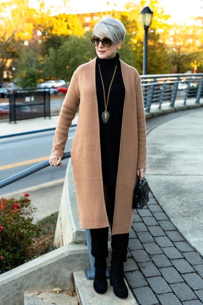 Camel long coat over black turtleneck and black trousers with black boots