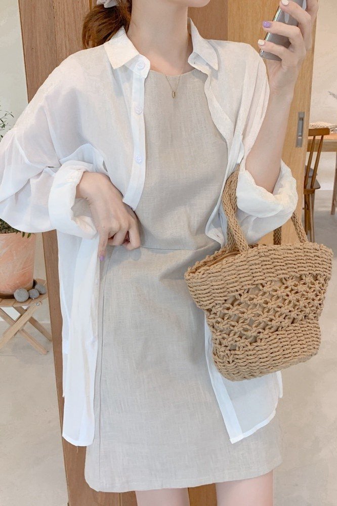 White linen shirt layered over grey slip dress with crochet bag for women over 60
