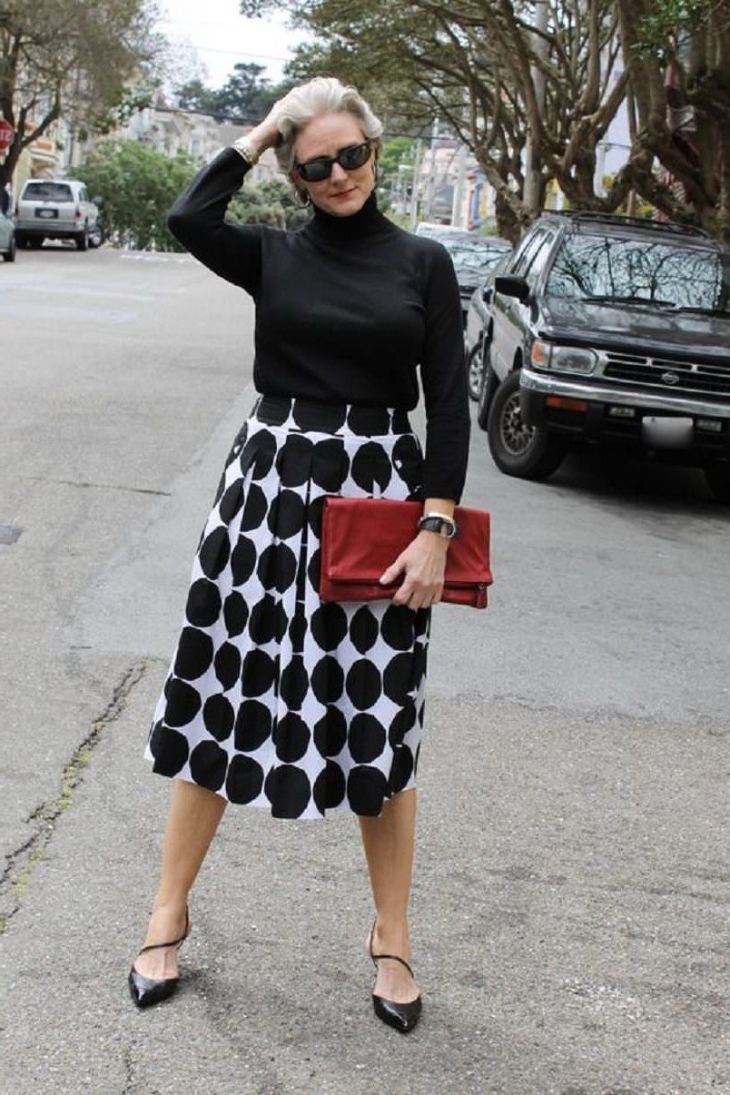 black turtleneck with polka dot midi skirt and red clutch, fun chic outfit for women over 50