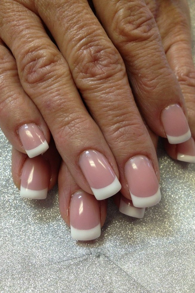 Close up of a classic French manicure on an older hand